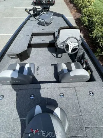 Slide: The Image of 2023 Vexus AVX181 boat interior with steering console and seating, parked outdoors. - 4