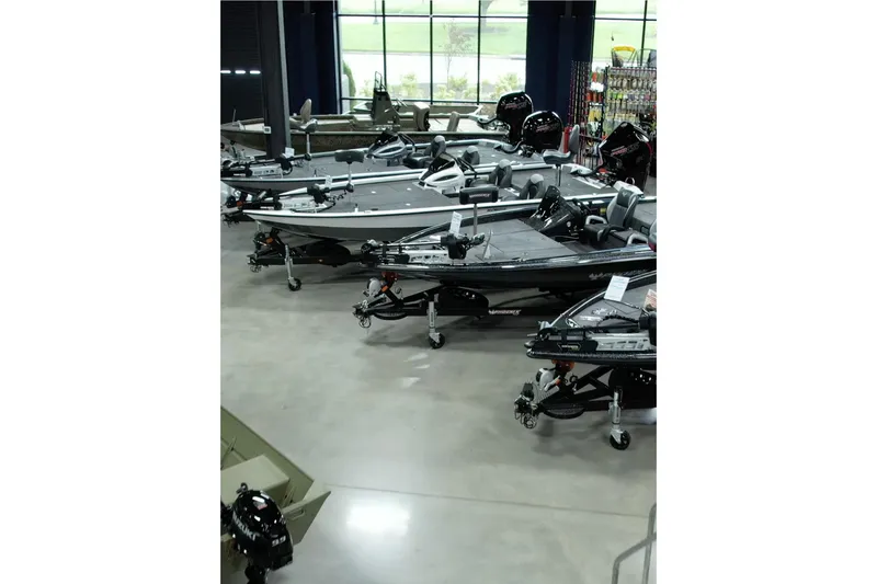 Slide: The Image of 2026 Bass Cat Pantera Classic boats displayed in a showroom with fishing equipment. - 16