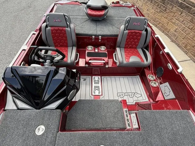 Slide: The Image of 2026 Bass Cat Lynx STS boat interior with red and gray seating, steering wheel, and carpeted flooring. - 13