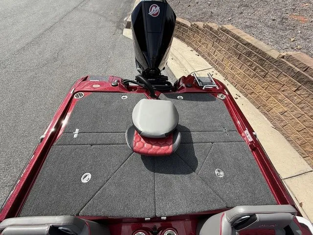 Slide: The Image of 2026 Bass Cat Lynx STS boat deck with seating, red and gray design, parked on pavement. - 15