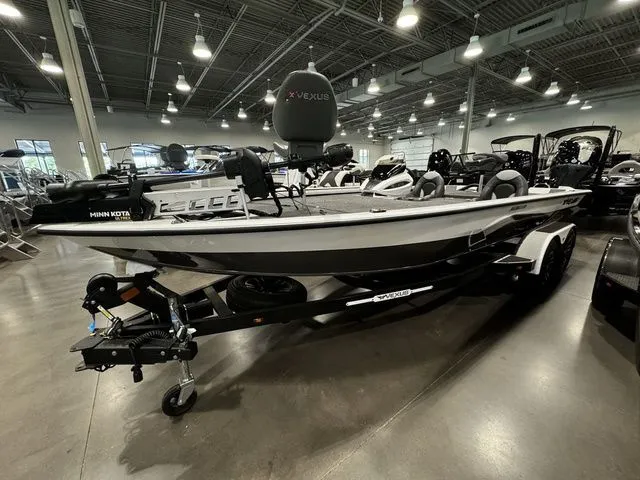 Slide: The Image of 2024 Vexus AVX1980C fishing boat displayed indoors with trailer and Minn Kota motor. - 1