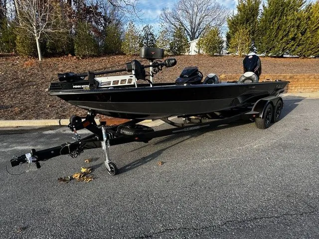 Slide: The Image of 2024 Vexus AVX2080 boat on trailer, parked outdoors, surrounded by trees. - 2