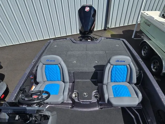 Slide: The Image of 2026 Ikon Boats LXE20 with blue seats and Mercury outboard motor, docked near a metal building. - 5