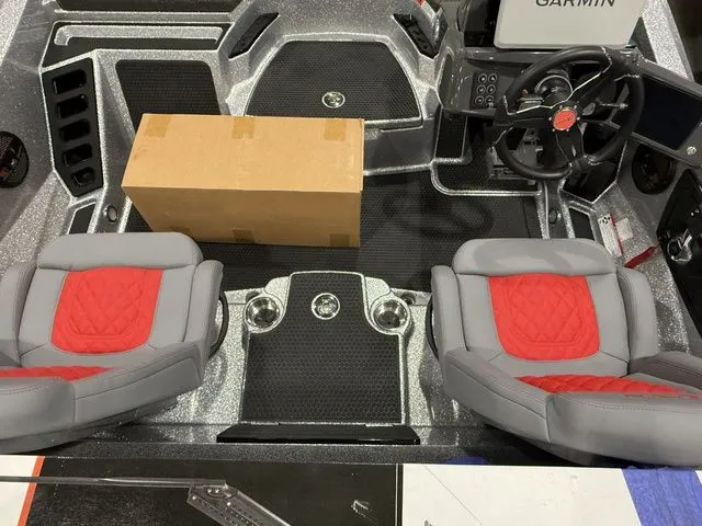 Slide: The Image of 2026 Ikon Boats LXE20 interior with red and gray seats, steering wheel, and cardboard box. - 9