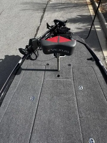 Slide: The Image of 2024 Vexus VXS20 boat deck with seat and trolling motor, parked on pavement. - 8