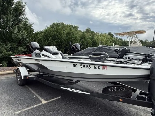 Slide: The Image of 2022 Vexus AVX1880 boat on trailer, parked outdoors with trees in background. - 2