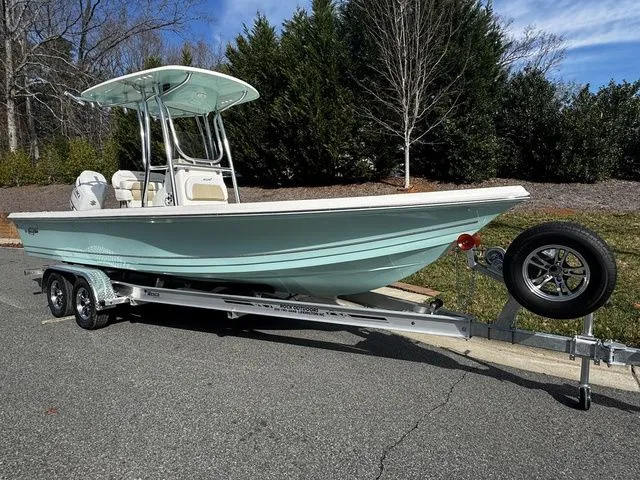 Slide: The Image of 2025 Bulls Bay 2400 boat on trailer, parked outdoors, with trees in the background. - 2