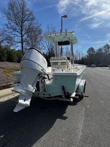 Slide: The Image of 2025 Bulls Bay 2400 boat with outboard motor on a trailer, parked on a sunny street. - 3