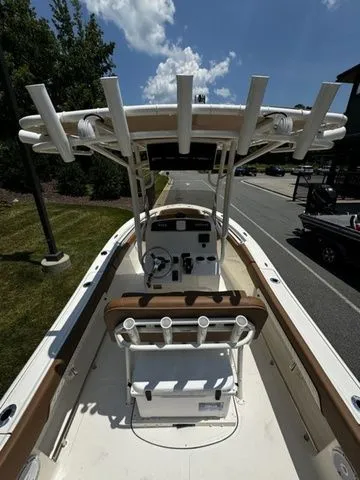 Slide: The Image of 2025 Pioneer ISLANDER 202 boat with center console and rod holders, parked outdoors. - 4