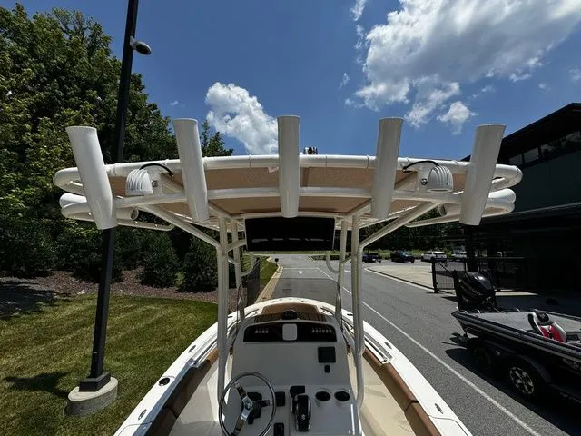 Slide: The Image of 2025 Pioneer ISLANDER 202 boat with T-top and rod holders, parked outdoors under a blue sky. - 6
