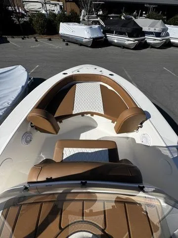 Slide: The Image of 2025 Pioneer Islander 180 boat with tan and white seating, docked among other boats. - 6