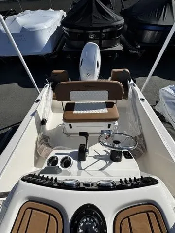 Slide: The Image of 2025 Pioneer Islander 180 boat interior with steering wheel and seating, docked among covered boats. - 9