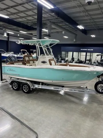 The Image of 2025 Pioneer Islander 222 boat in showroom, turquoise hull, dual-axle trailer, modern design. - 1