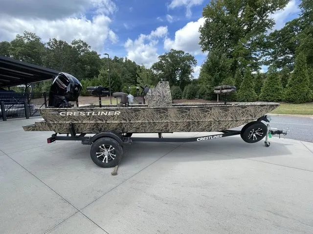 The Image of 2023 Crestliner 1860 Retriever CC boat on trailer, camo design, parked outdoors. - 1