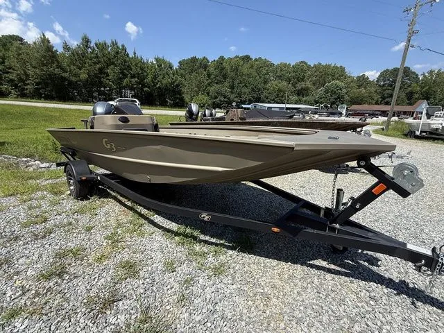 Slide: The Image of 2023 G3 Gator Tough 17 SC boat on trailer, parked on gravel, surrounded by greenery. - 2