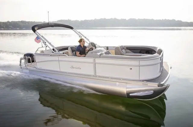 The Image of 2025 Barletta Aria A22QC pontoon boat cruising on a calm lake. - 1