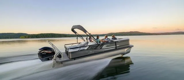 The Image of 2024 SunCatcher Select 322SS pontoon boat cruising on a serene lake at sunset. - 1