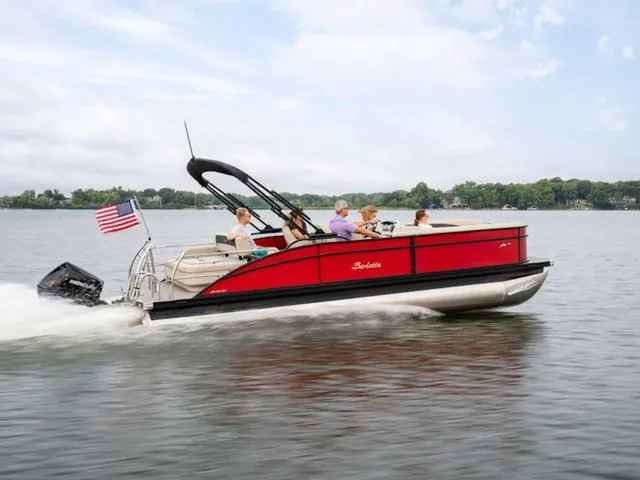 The Image of 2025 Barletta Boats A20UC pontoon cruising on a lake with passengers and American flag. - 1