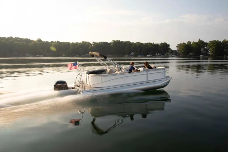Slide: The Image of 2025 Barletta ARIA A20QC pontoon boat cruising on a serene lake at sunset. - 8