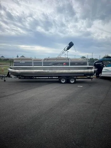 The Image of 2015 Sun Tracker PARTY BARGE® 24 XP3 pontoon boat on trailer, parked outdoors. - 1