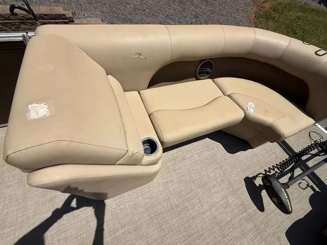 Slide: The Image of 2016 Bennington 22 SSX boat interior with beige seating, cup holder, and visible wear. - 14
