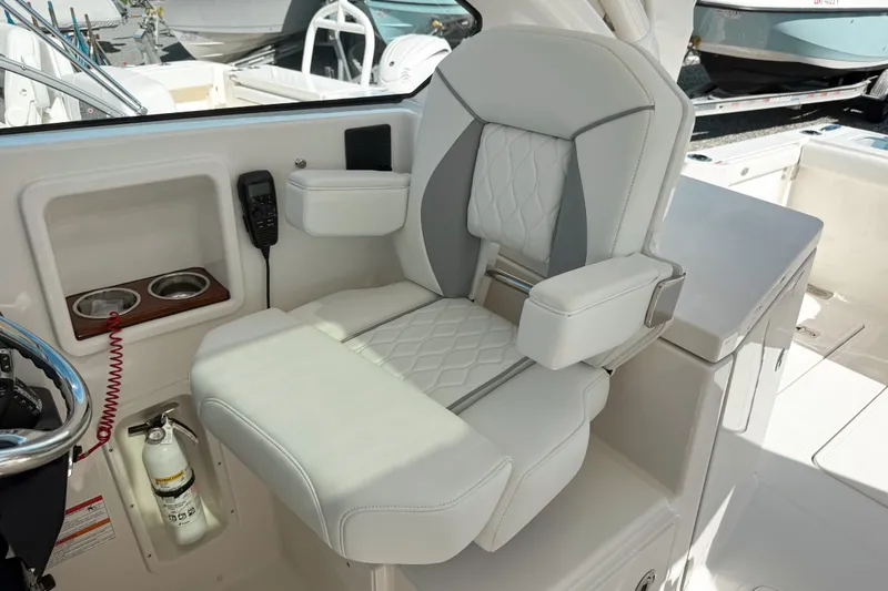 Slide: The Image of Luxurious seating on 2026 Pursuit DC 306 Dual Console boat, featuring cup holders and fire extinguisher. - 13