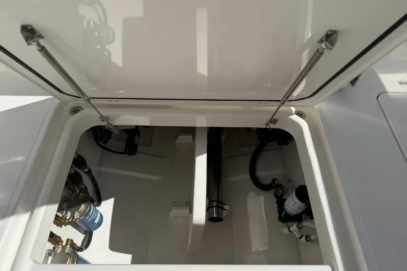 Slide: The Image of 2026 Pursuit DC 306 Dual Console storage compartment with visible mechanical components. - 22