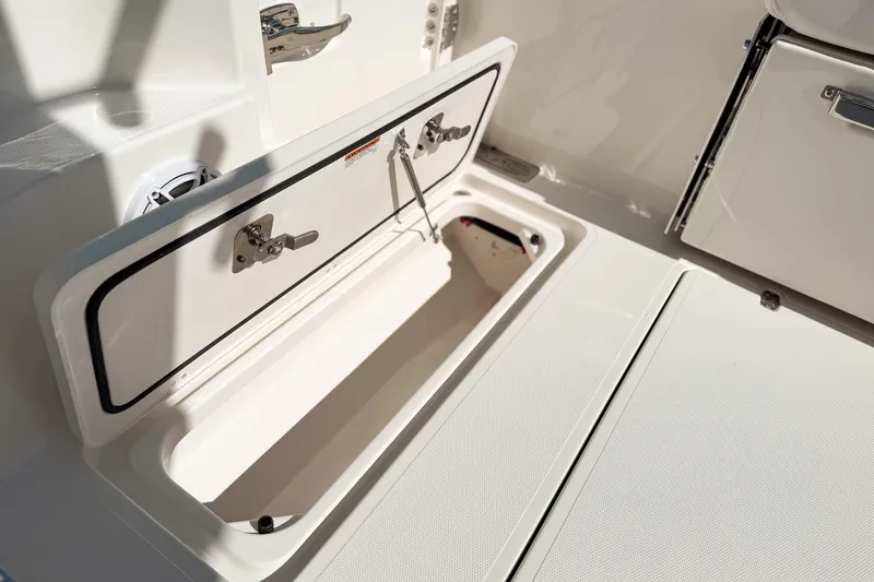 Slide: The Image of 2026 Pursuit DC 306 Dual Console boat storage compartment open, showcasing interior details. - 23