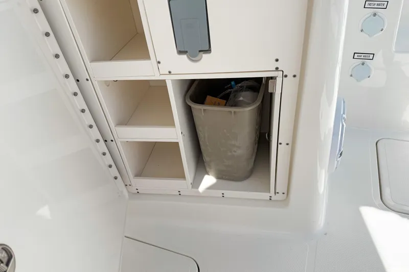Slide: The Image of Storage compartment on 2026 Pursuit DC 306 Dual Console boat with trash bin. - 4