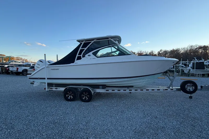 Slide: The Image of 2022 Pursuit DC 266 Dual Console boat on trailer, parked outdoors. - 28