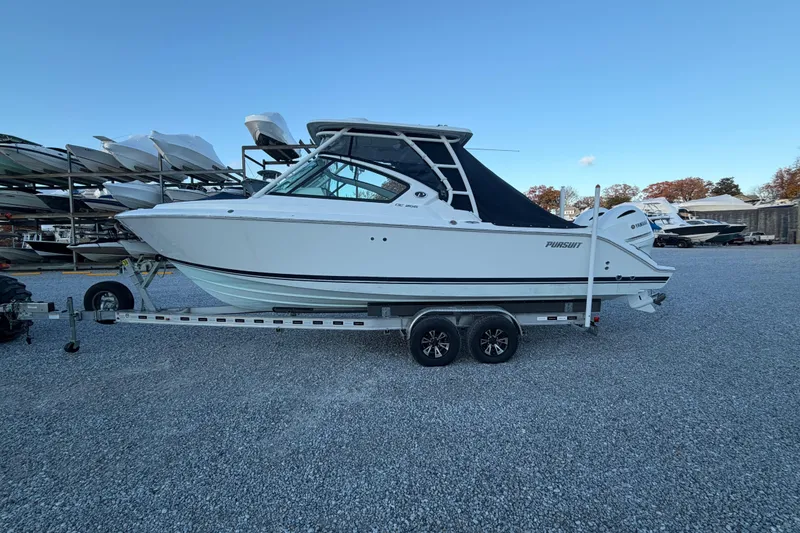 Slide: The Image of 2022 Pursuit DC 266 Dual Console boat on trailer, parked on gravel lot. - 30