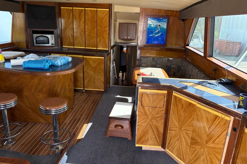Slide: The Image of Interior of a 1994 Bertram 60 Convertible yacht with wood paneling and bar stools. - 10