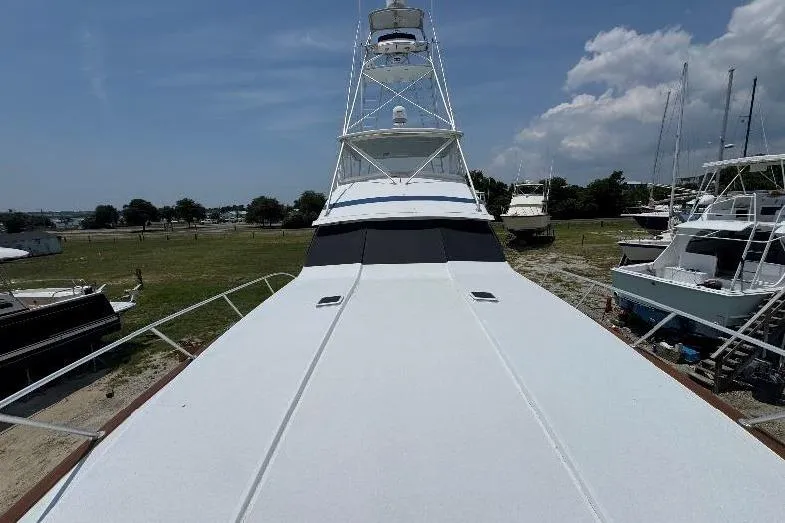 Slide: The Image of 1994 Bertram 60 Convertible yacht on land, showcasing its expansive deck and tower. - 3