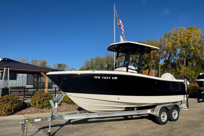 Slide: The Image of 2024 Robalo R230 Center Console boat on trailer, parked outdoors under clear blue sky. - 1