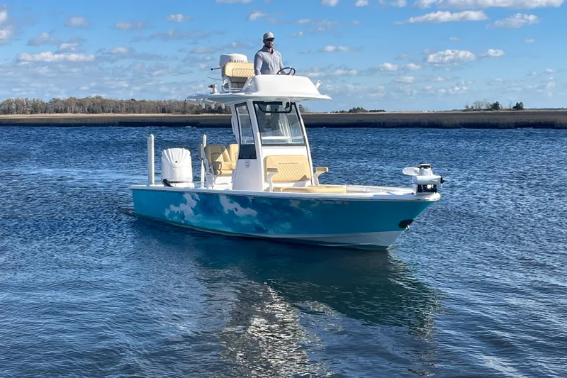 Slide: The Image of 2024 Sportsman Masters 247OE Bay Boat cruising on a calm, scenic waterway. - 2