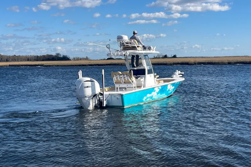 Slide: The Image of 2024 Sportsman Masters 247OE Bay Boat cruising on a serene waterway under a clear blue sky. - 5