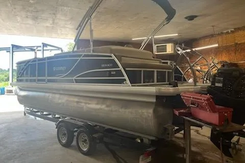 The Image of 2020 MONACO 235C pontoon boat on trailer in a garage setting. - 1