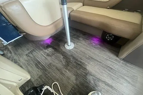 Slide: The Image of 2020 MONACO 235C interior with beige seating, wood flooring, and purple LED lights. - 4