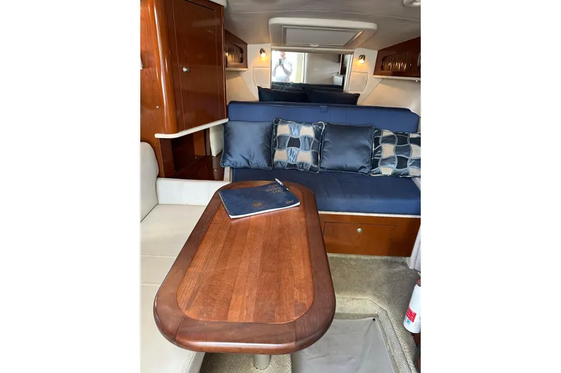Slide: The Image of Interior of 2008 Sea Ray 290 Sundancer with wooden table and blue cushioned seating. - 13
