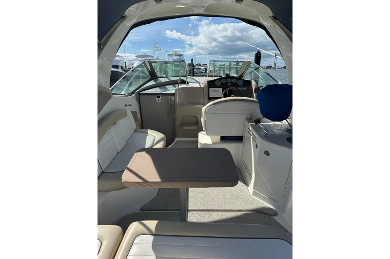 Slide: The Image of 2008 Sea Ray 290 Sundancer interior with seating, table, and helm, docked at marina. - 7