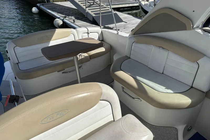 Slide: The Image of 2008 Sea Ray 290 Sundancer boat interior with beige seating and table, docked by the water. - 8