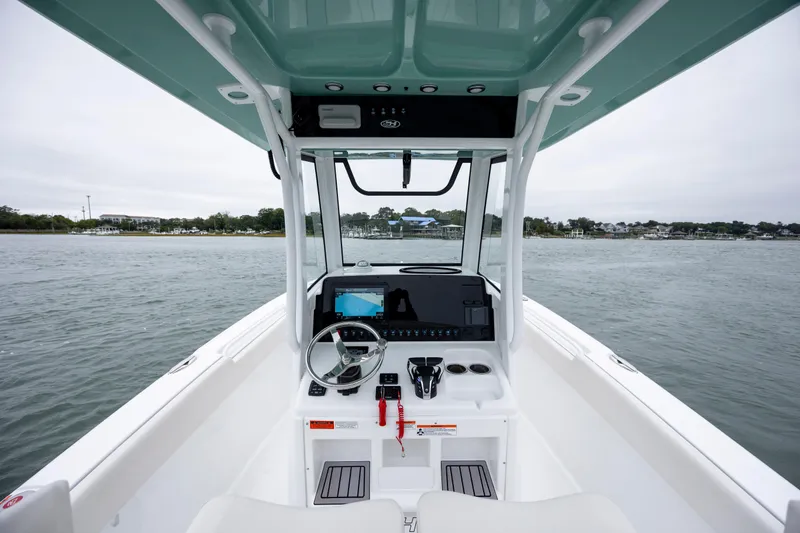 Slide: The Image of 2023 Sea Hunt Ultra 265 SE boat interior with steering console on calm water. - 14