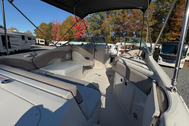 Slide: The Image of 2004 Sea Ray 240 Sundeck interior with seating, canopy, and steering wheel, surrounded by autumn trees. - 10