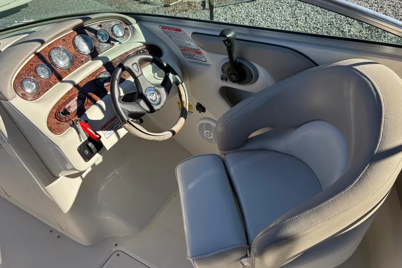 Slide: The Image of 2004 Sea Ray 240 Sundeck helm with steering wheel, gauges, and comfortable captain's chair. - 12