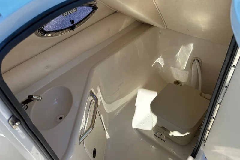 Slide: The Image of 2004 Sea Ray 240 Sundeck interior bathroom with sink and portable toilet. - 13