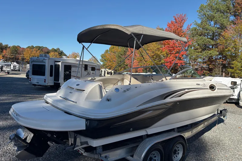 Slide: The Image of 2004 Sea Ray 240 Sundeck boat on trailer, parked near RVs, autumn trees in background. - 6
