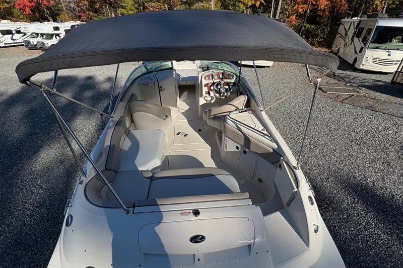 Slide: The Image of 2004 Sea Ray 240 Sundeck boat with canopy, parked on gravel, surrounded by RVs and autumn trees. - 9