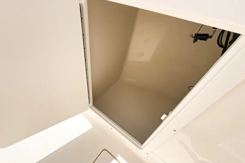 Slide: The Image of 2025 Cobia 220 Dual Console storage compartment, open and empty, showcasing interior space. - 16