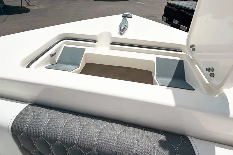 Slide: The Image of 2025 Cobia 220 Dual Console boat interior with storage compartment and cushioned seating. - 20