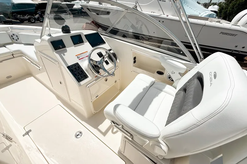 Slide: The Image of 2025 Cobia 220 Dual Console boat interior with steering wheel and white seating. - 9